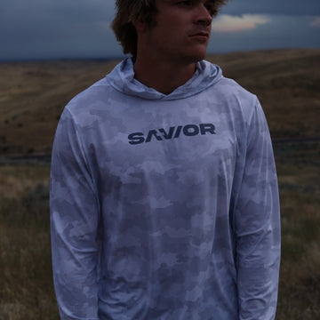 Person wearing a hoodie with 'SAVIOR' branding in a field