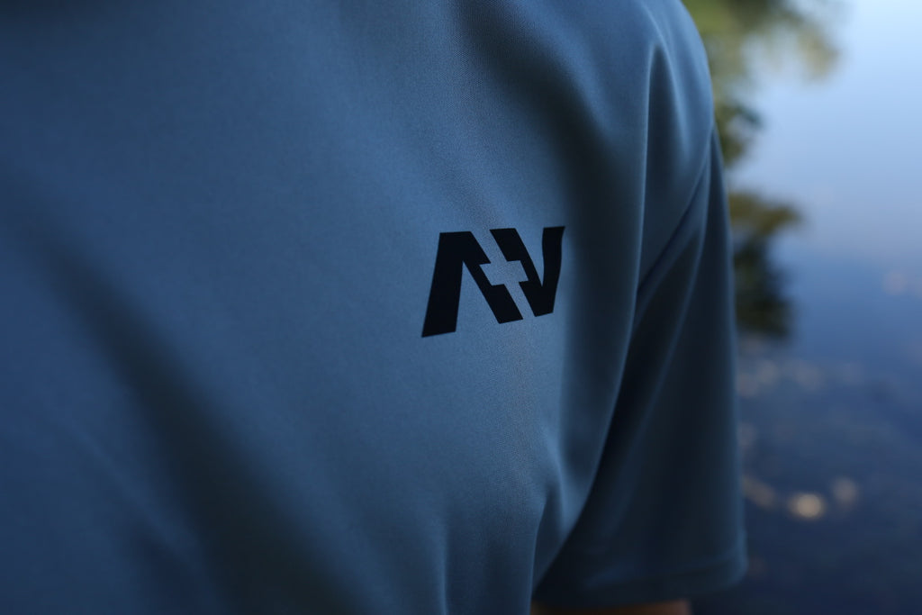 shirt with a black logo on the sleeve against a blurred natural background