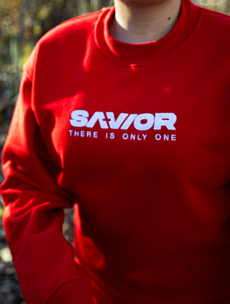 Red sweatshirt with 'SAVIOR THERE IS ONLY ONE' text worn by a person outdoors.